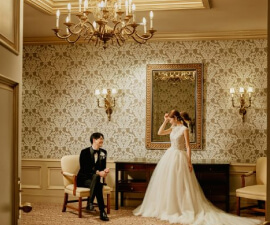 クラシカルな壁紙の前で笑顔を見せる新郎新婦