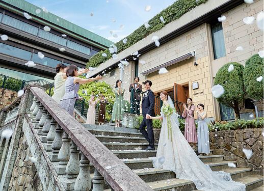 石段でフラワーシャワーを受ける新郎新婦と参列者たちの祝福シーン