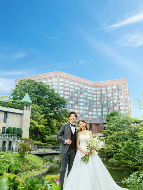 青空とホテル建物を背景にした新郎新婦の記念撮影