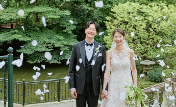 花びらが舞う中、庭園で笑顔を見せる新郎新婦