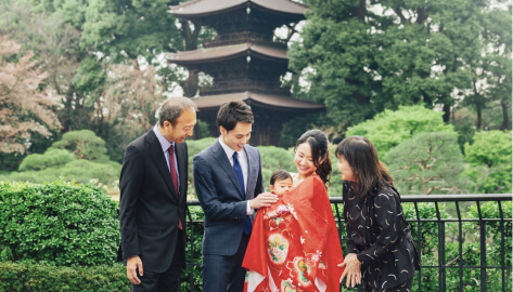 五重塔を背景に赤い着物の赤ちゃんを抱く家族写真