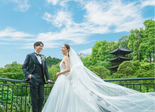新郎新婦が青空と緑豊かな庭園を背景に笑顔で寄り添うウェディングの様子