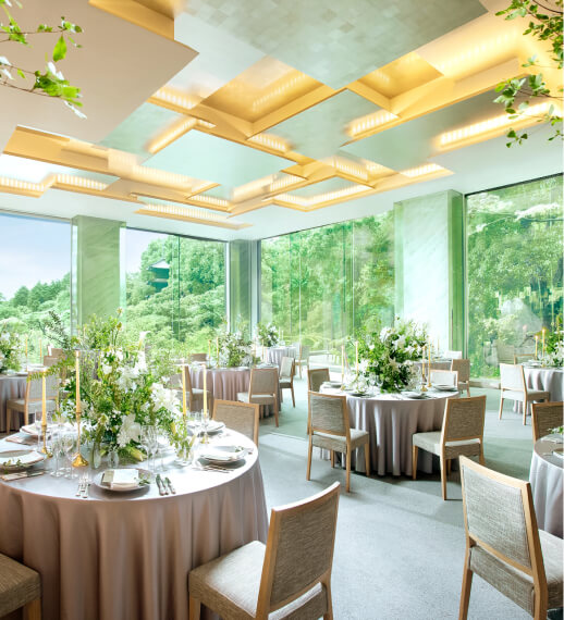 大きな窓から緑が見える明るい披露宴会場のテーブルセッティング