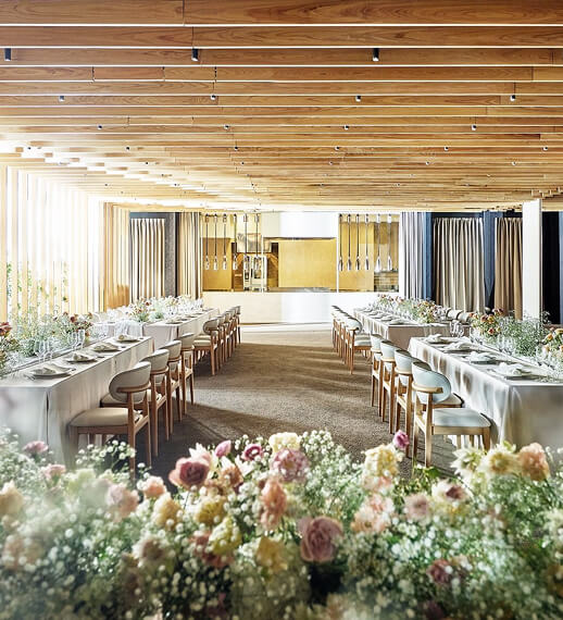 白い花で装飾されたモダンな披露宴会場、長テーブルレイアウトと洗練されたテーブルセッティング