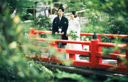 五重塔を背景に緑豊かな日本庭園で撮影する新郎新婦