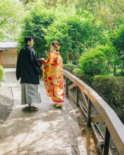 木漏れ日の中、緑の小道を歩く和装の新郎新婦