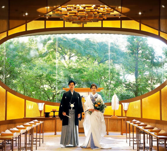 黄金色の光に包まれた神殿風チャペルで並ぶ和装の新郎新婦