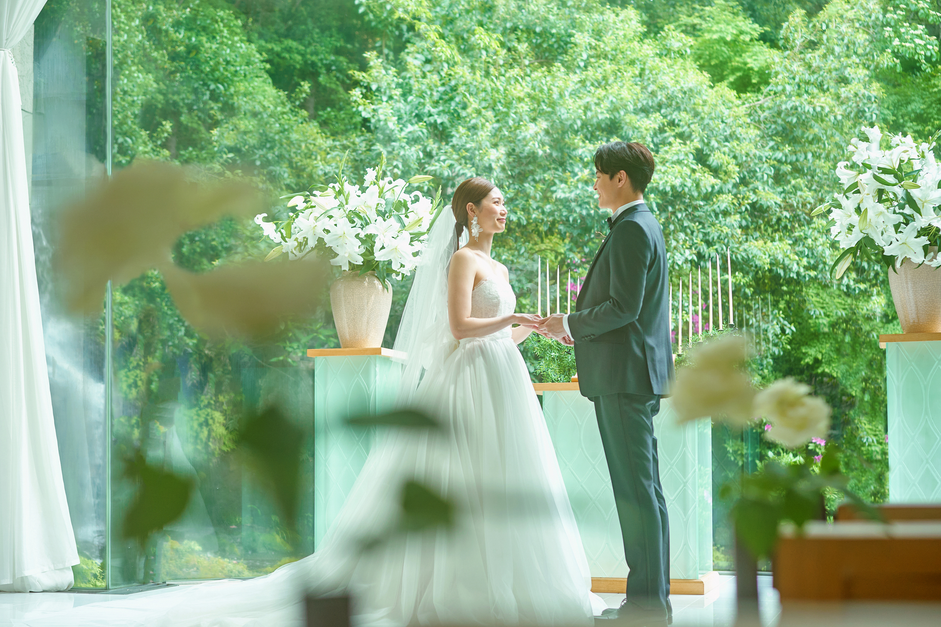 緑あるチャペルで向かい合う花嫁と花婿