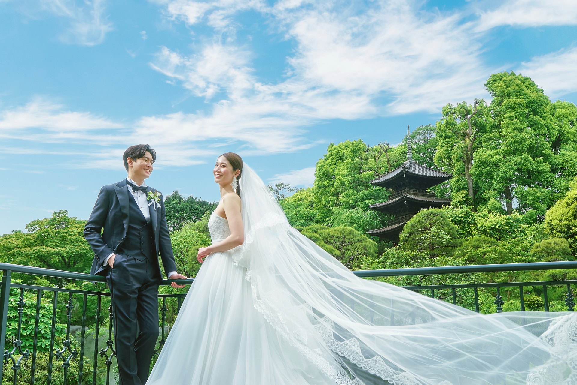 青空のもと撮影する新郎新婦